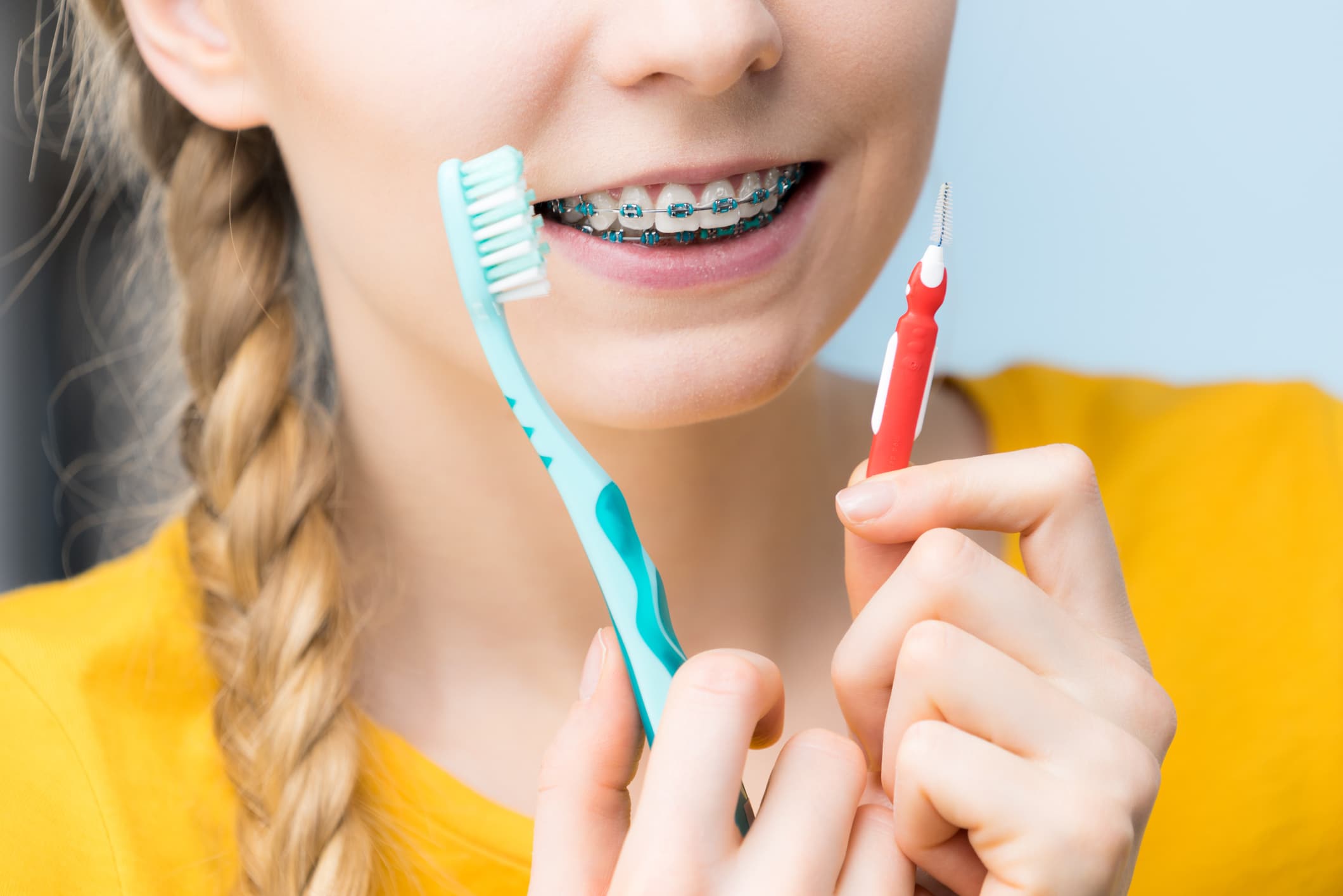 Woman smiling cleaning teeth with braces
