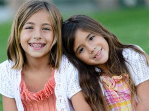 young girl with braces smiling with younger sister
